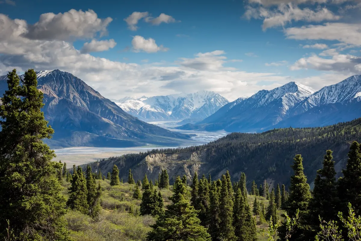 A dramatic mountain trail winding through high rocky peaks under a bright blue sky