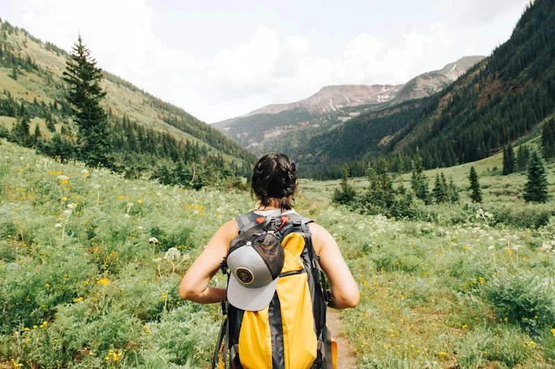 A professional flat lay of camping gear including a mountain backpack, stove, and map laid out on a rock